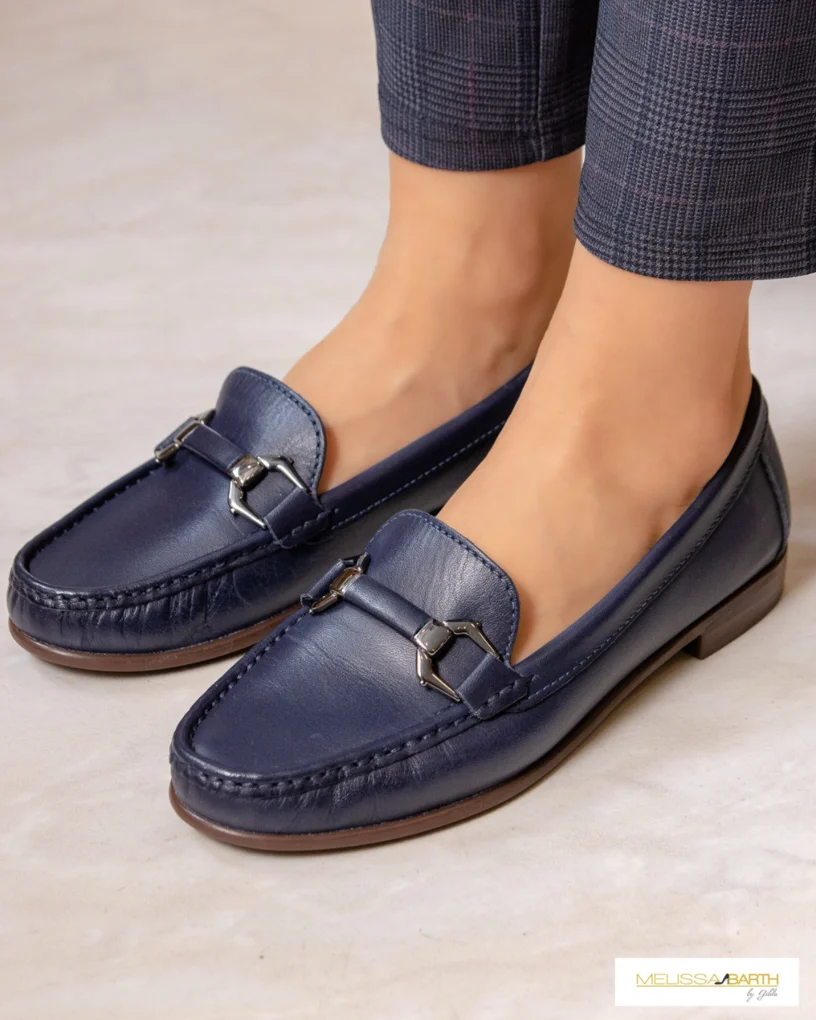 Foto enquadrada nos pes de uma modelo calçando um mocassim azul escuro de couro